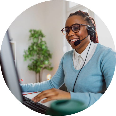 Woman in blue sweater smiling while talking into a headset 