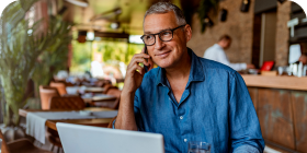 Man in blue shirt, wearing glasses, and talking on a cell phone