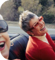 Woman in red sweater and sunglasses laughing in a car